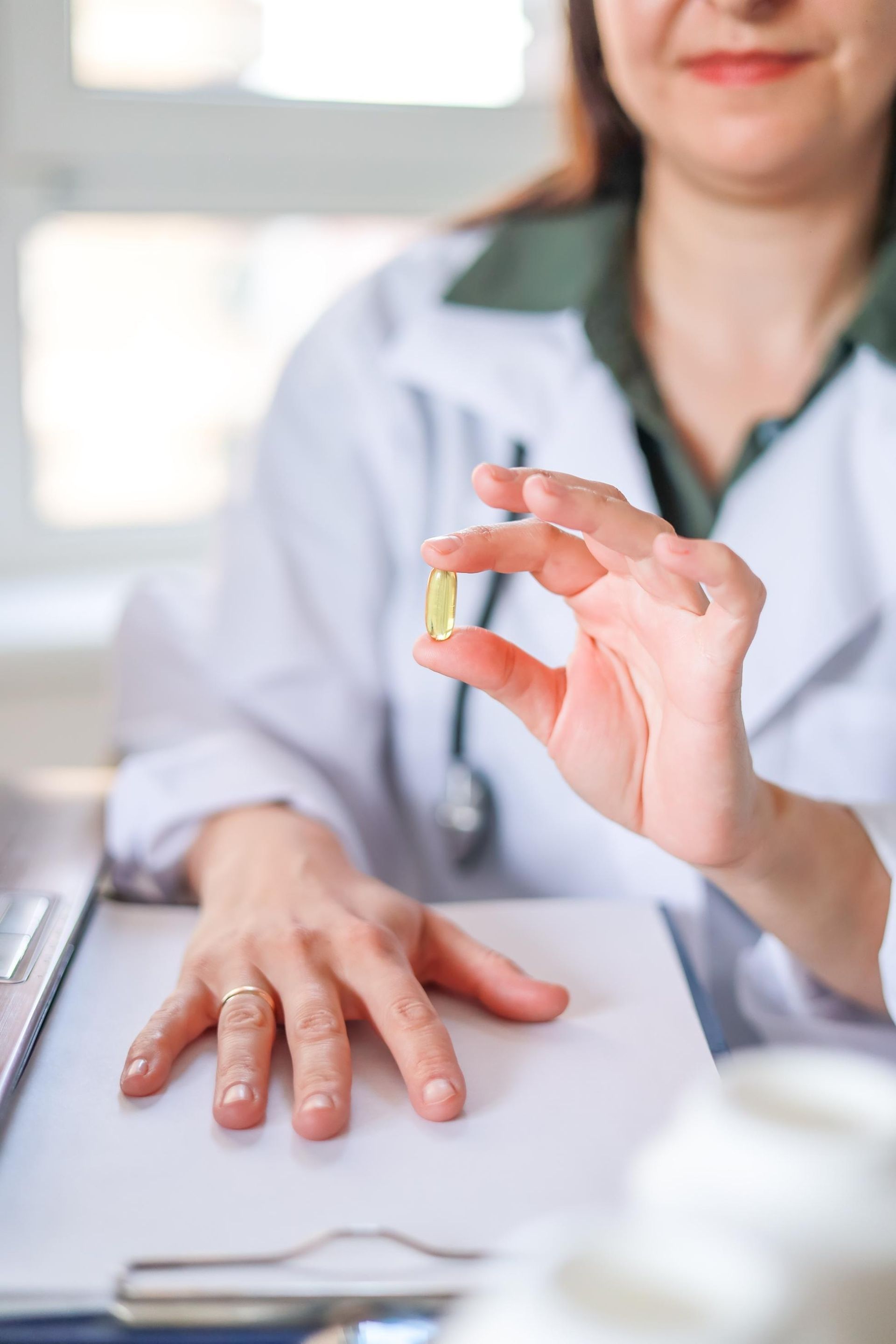 A female doctor is holding a pill in her hand.